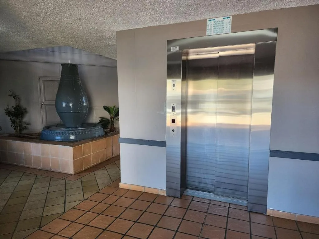 Modern elevator and decorative blue vase in building lobby entrance