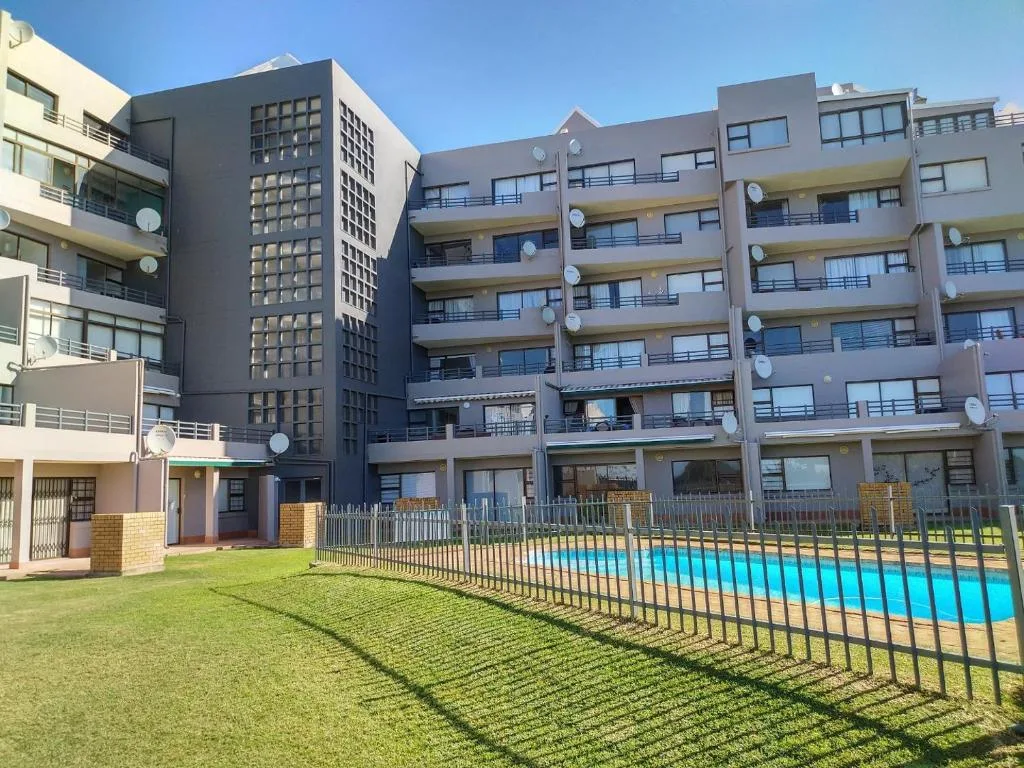 Modern apartment building with pool and manicured lawn in Mossel Bay