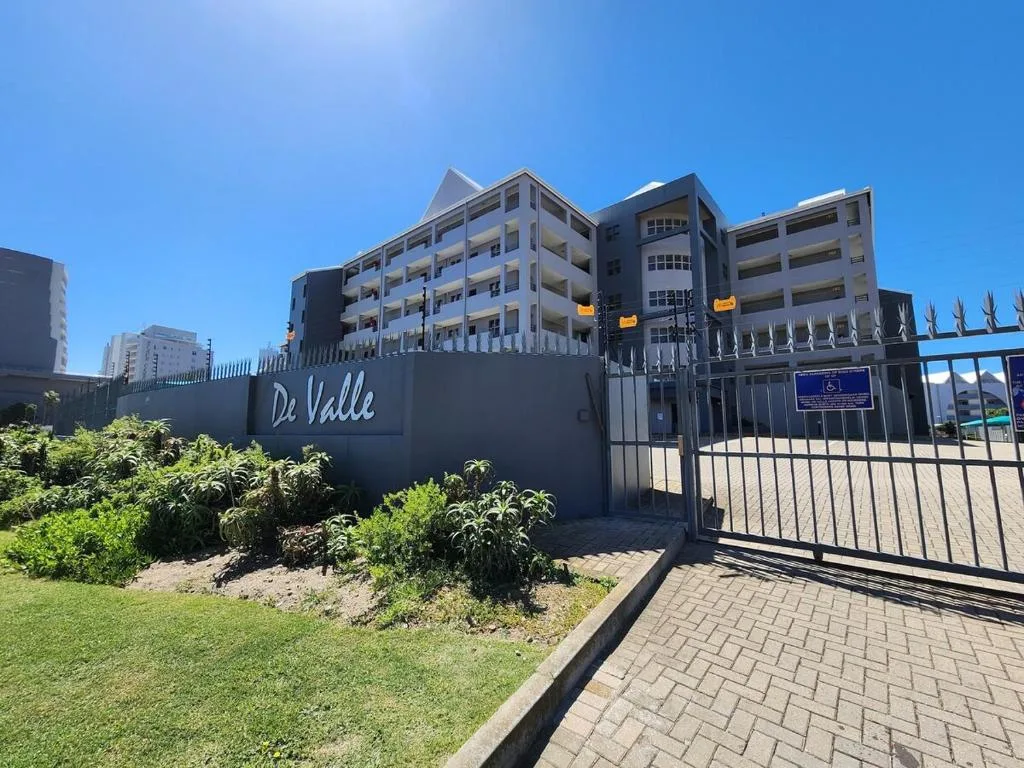 Modern apartment building entrance with De Valle signage and security gate