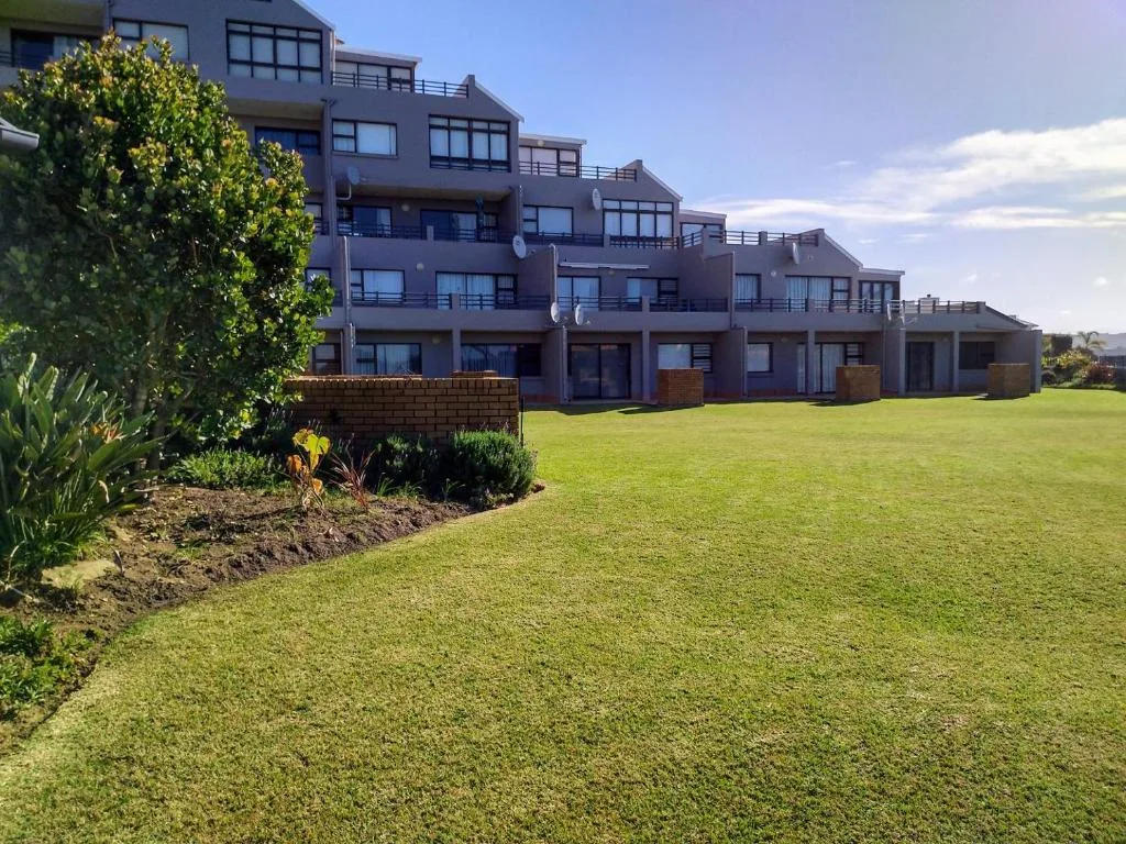 Modern multi-story residential building with manicured lawns and landscaping