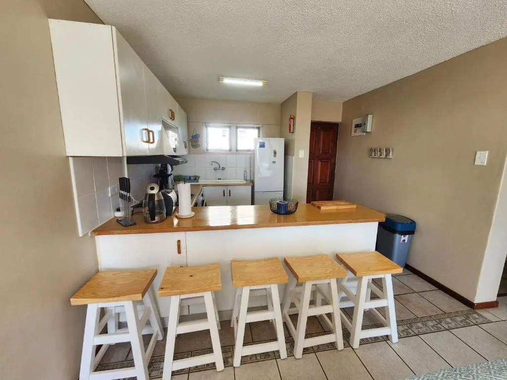 Open kitchen with white cabinetry, wooden countertop, and bar seating stools