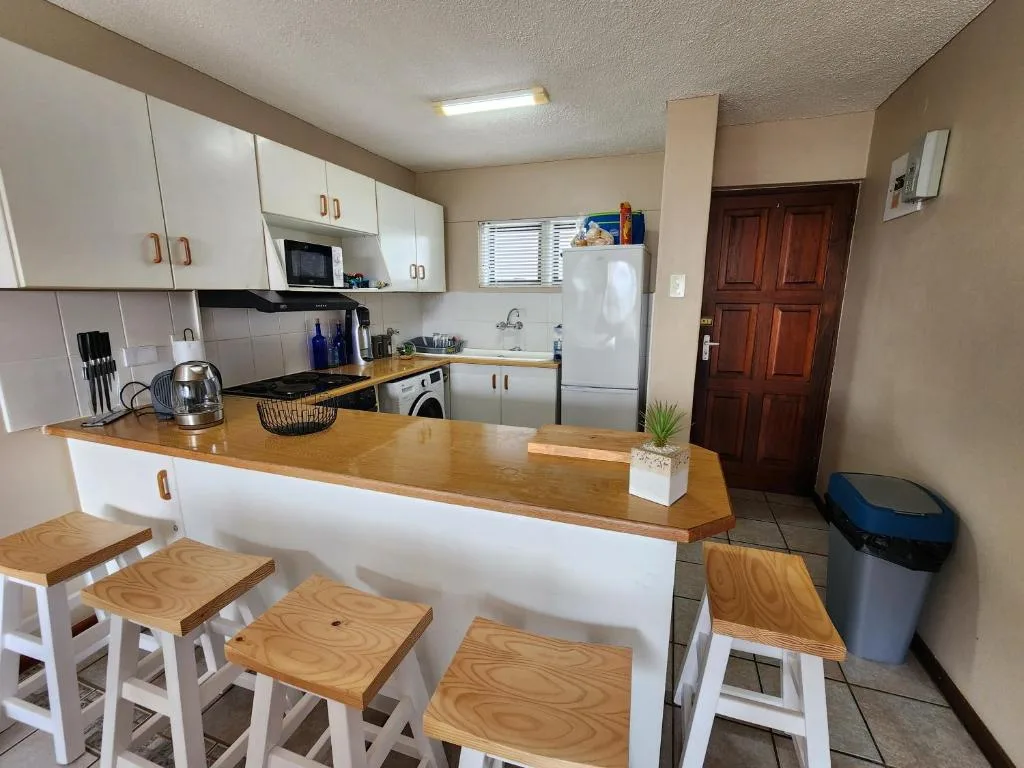 Open-plan kitchen with white cabinetry, wooden counter, and bar seating