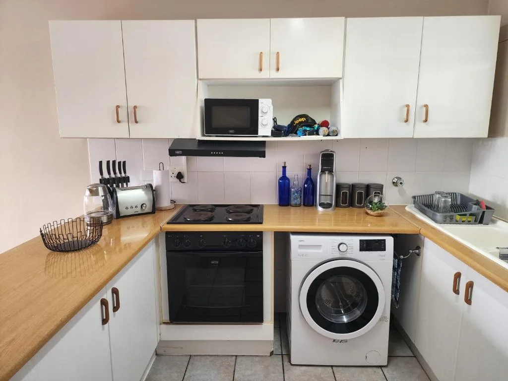 Modern kitchen with white cabinetry, wooden countertop, black oven and washing machine