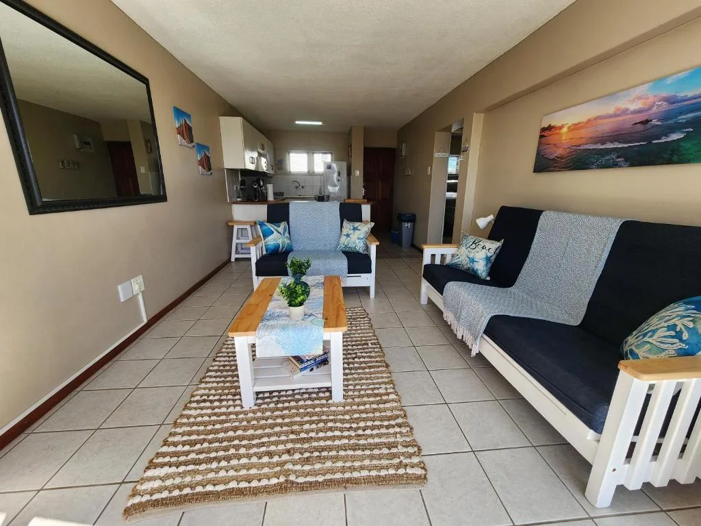 Open-plan lounge with sofas, coffee table, and kitchen visible beyond