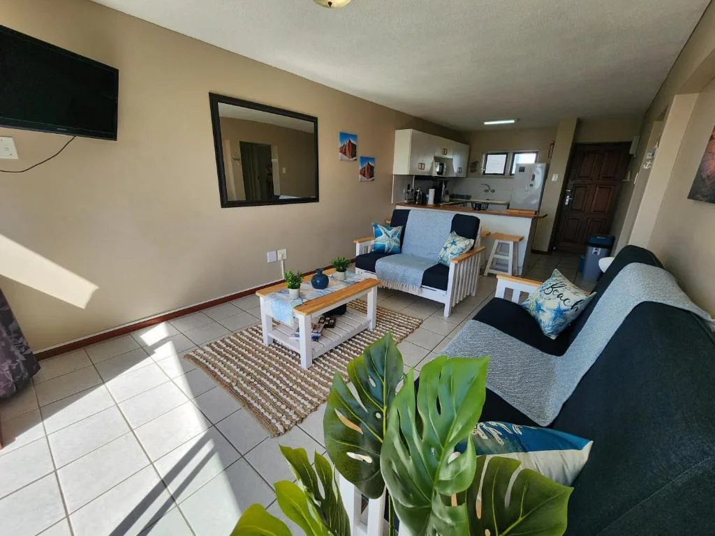 Bright living room with seating, TV, and open kitchen area visible