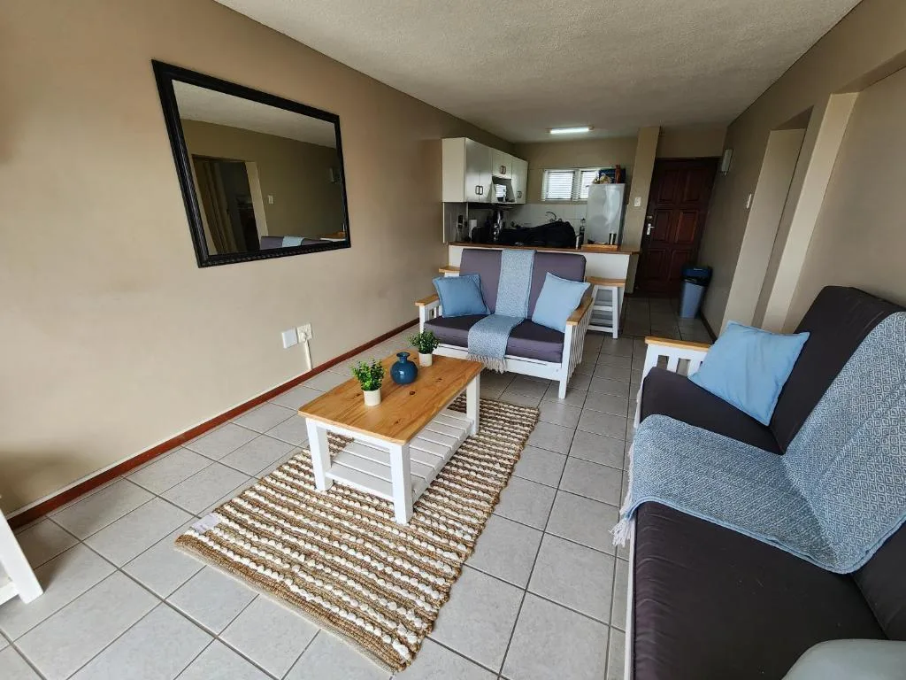 Open-plan lounge with sofas, coffee table, and kitchenette visible in background