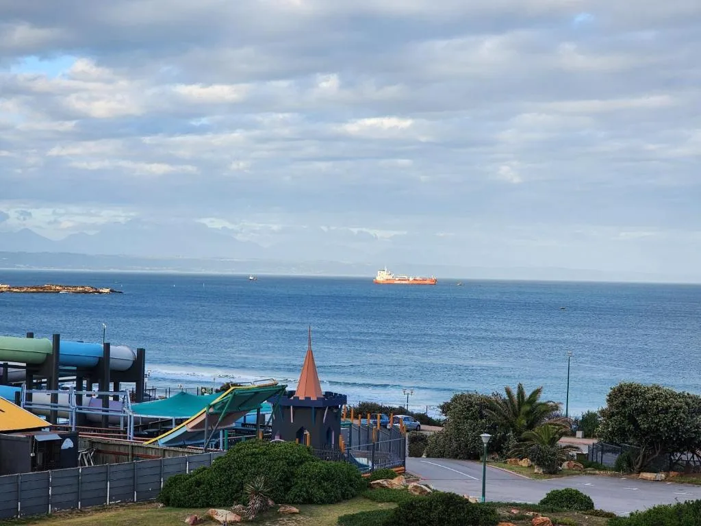 Panoramic ocean view with mountains, beach, and ships on horizon
