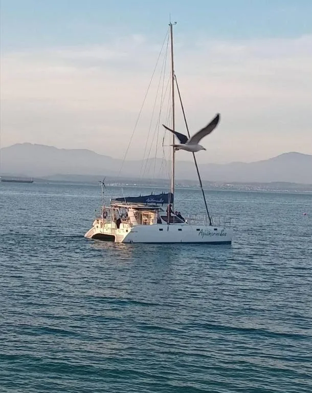 Sailboat anchored in calm blue water with mountains in distant background