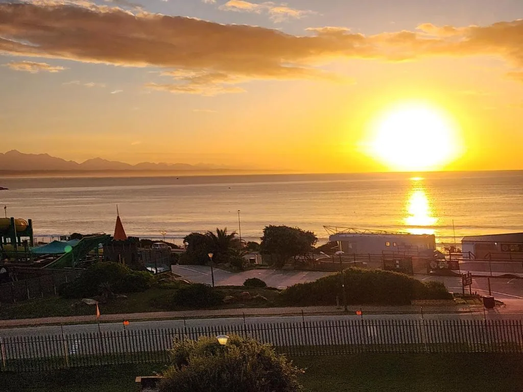 Stunning sunset over ocean with mountains and coastal town below