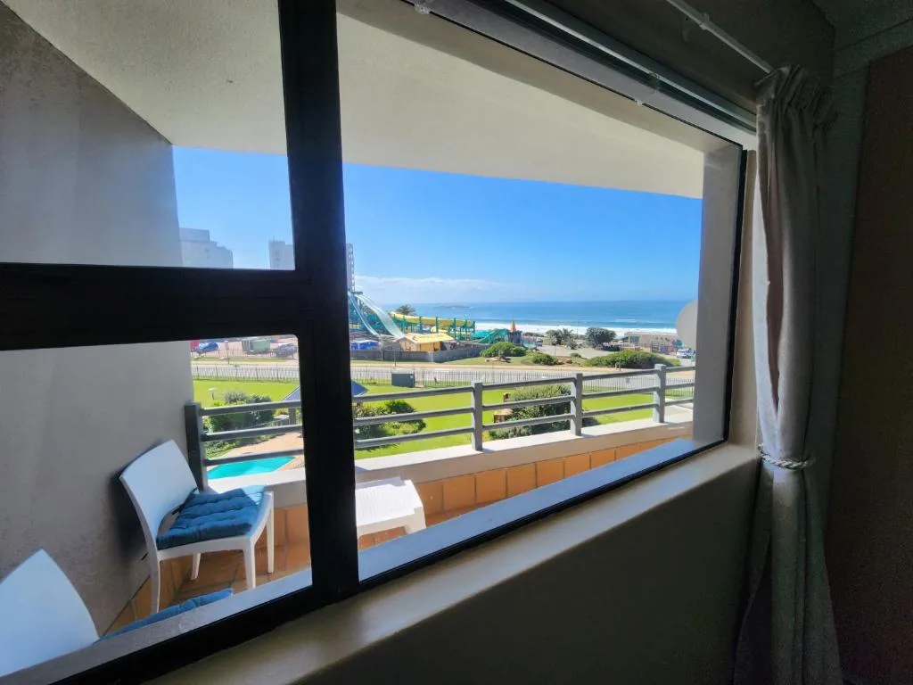 Panoramic ocean and beach view from interior window with railing