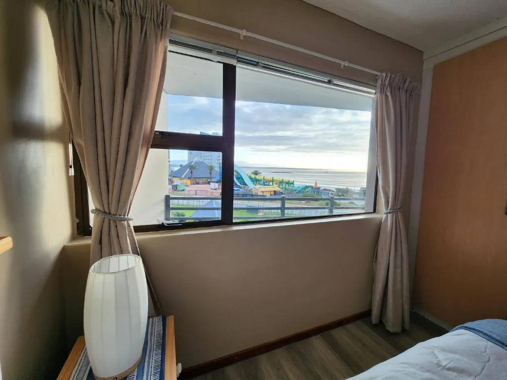 Expansive sea and lagoon view through large bedroom window with curtains