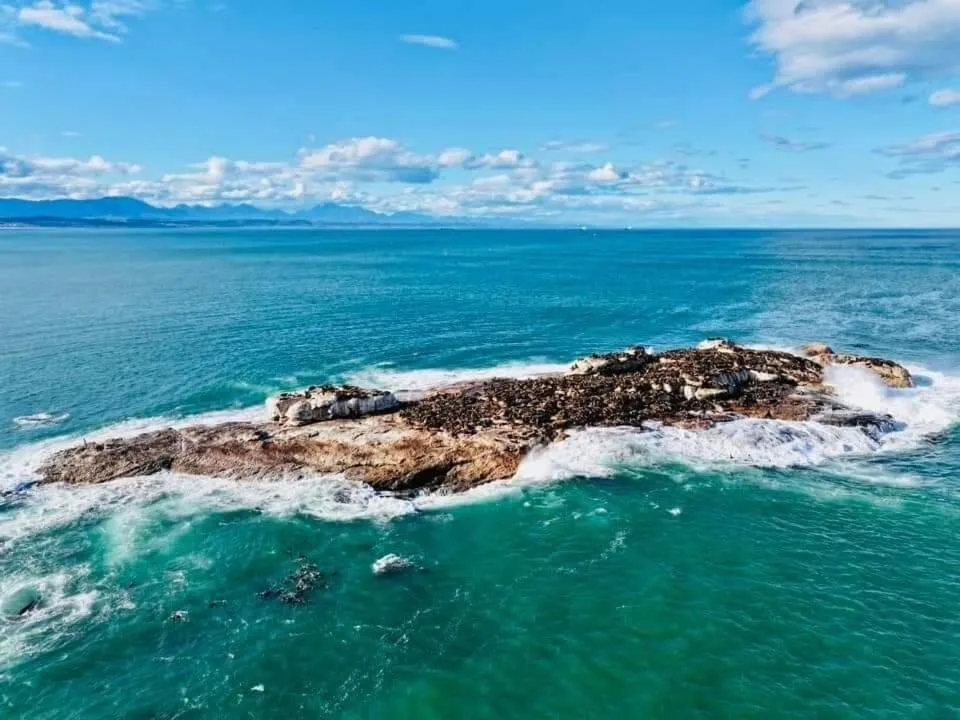 Turquoise ocean waters with rocky outcrops and distant mountain range