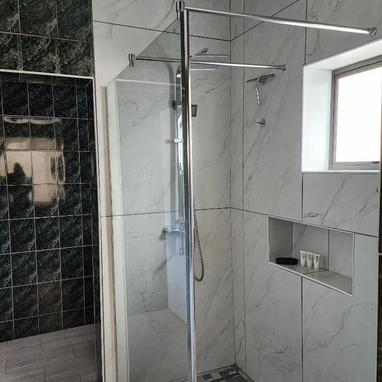 Modern shower enclosure with marble tiles and rainfall showerhead