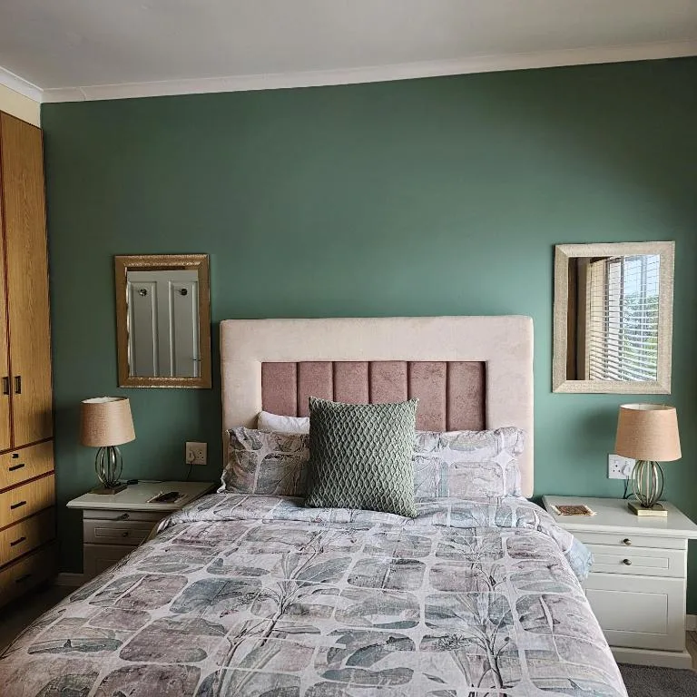 Contemporary bedroom with green accent wall, upholstered headboard, and bedside tables