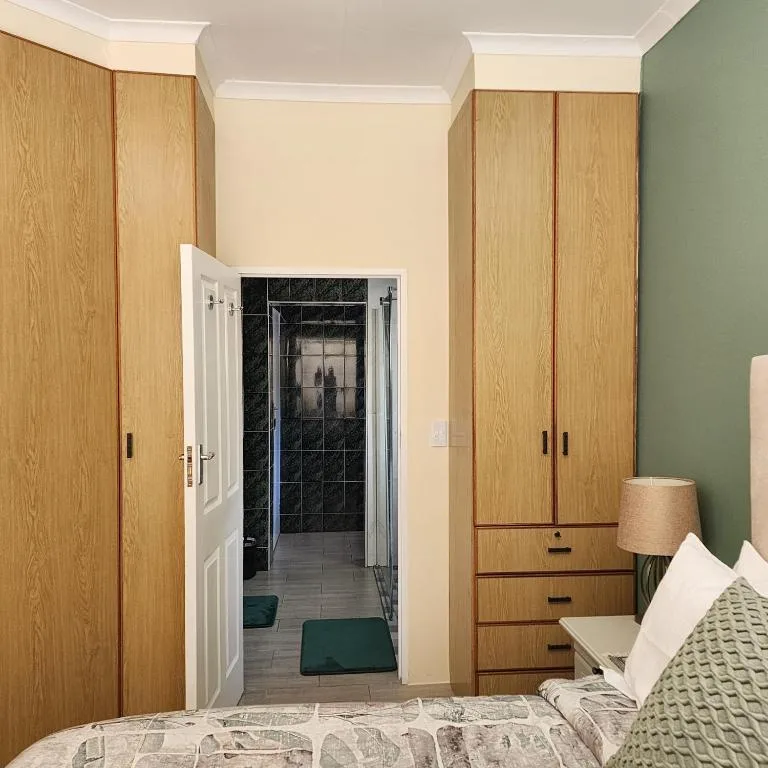 Spacious bedroom with wooden wardrobes and ensuite bathroom visible