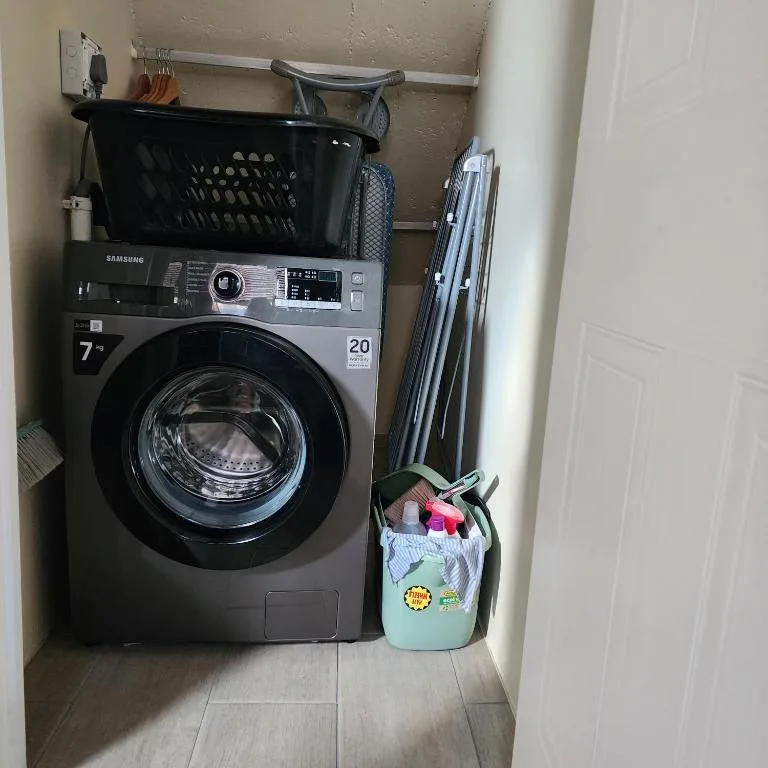 Modern Samsung washing machine in utility room with laundry supplies