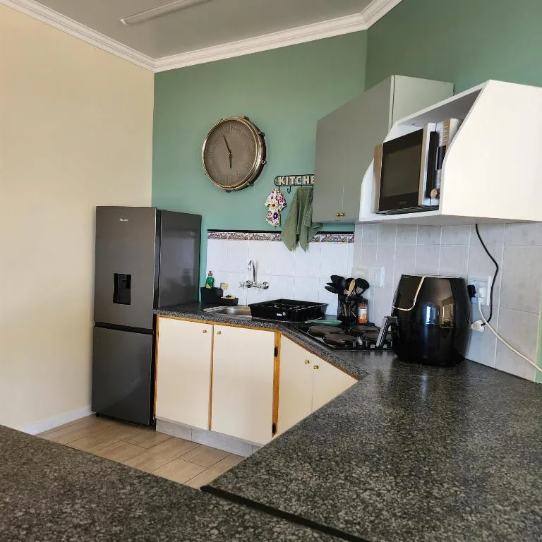Modern kitchen with stainless steel appliances, granite counters, and mint green walls