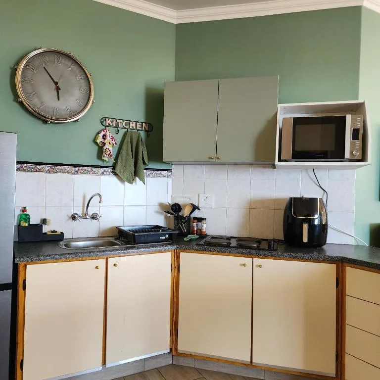 Kitchen with cream cabinets, white tile backsplash, microwave, and wall clock