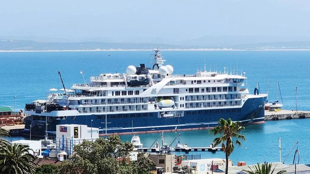 Turquoise ocean and luxury cruise ship docked at Mossel Bay harbor