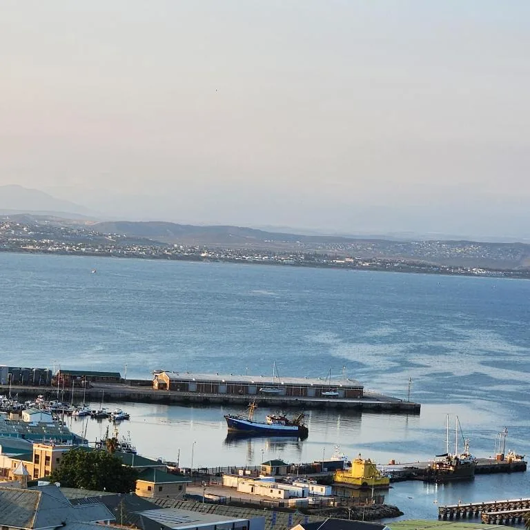 Scenic coastal view of Mossel Bay harbor with boats and distant mountains