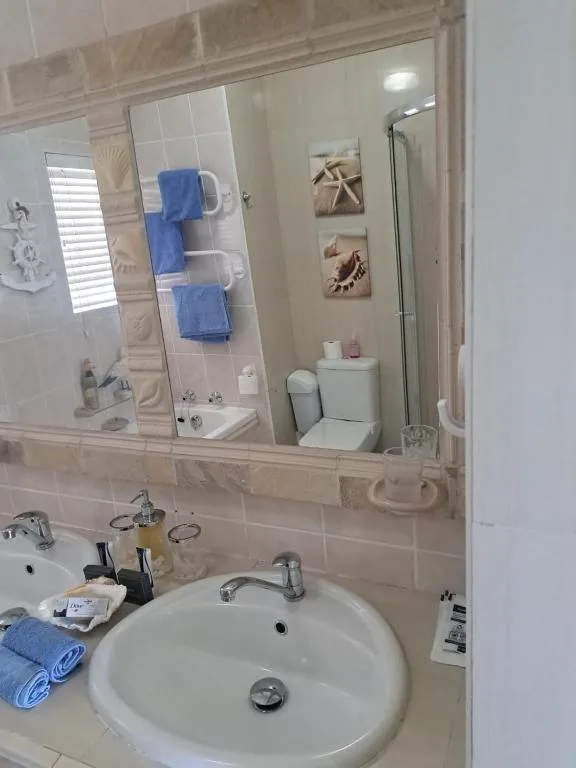 Clean bathroom with round sink, large mirror, and blue towels on rack