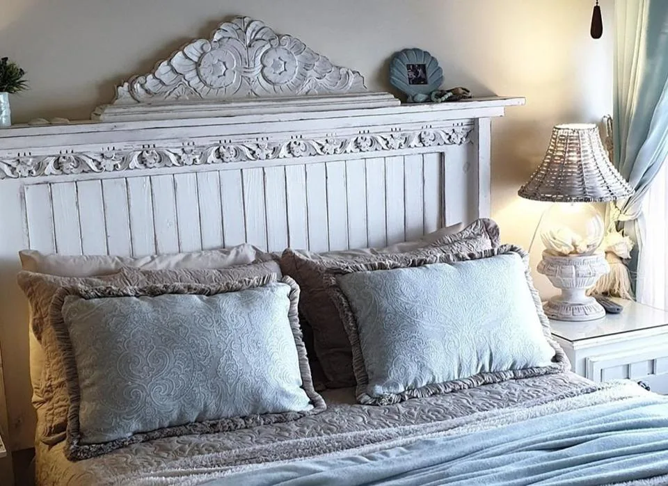 Ornate white wooden bed with decorative headboard and patterned pillows