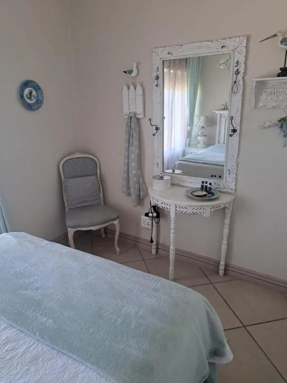 Bedroom with bed, vanity mirror, and decorative white chair