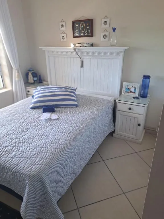 Bright bedroom with queen bed, striped pillows, white headboard and nightstand