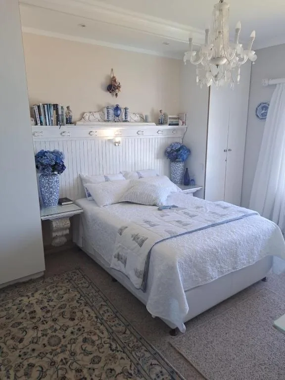 Bright bedroom with queen bed, white bedding, crystal chandelier above