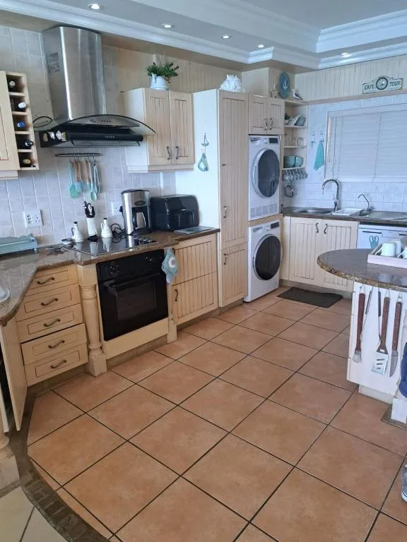 Bright kitchen with wooden cabinetry, stainless steel appliances, and stacked washer dryer