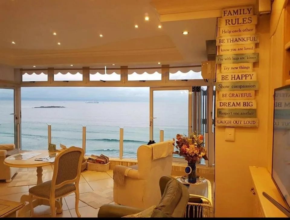 Bright lounge with ocean view through large glass doors and family rules sign