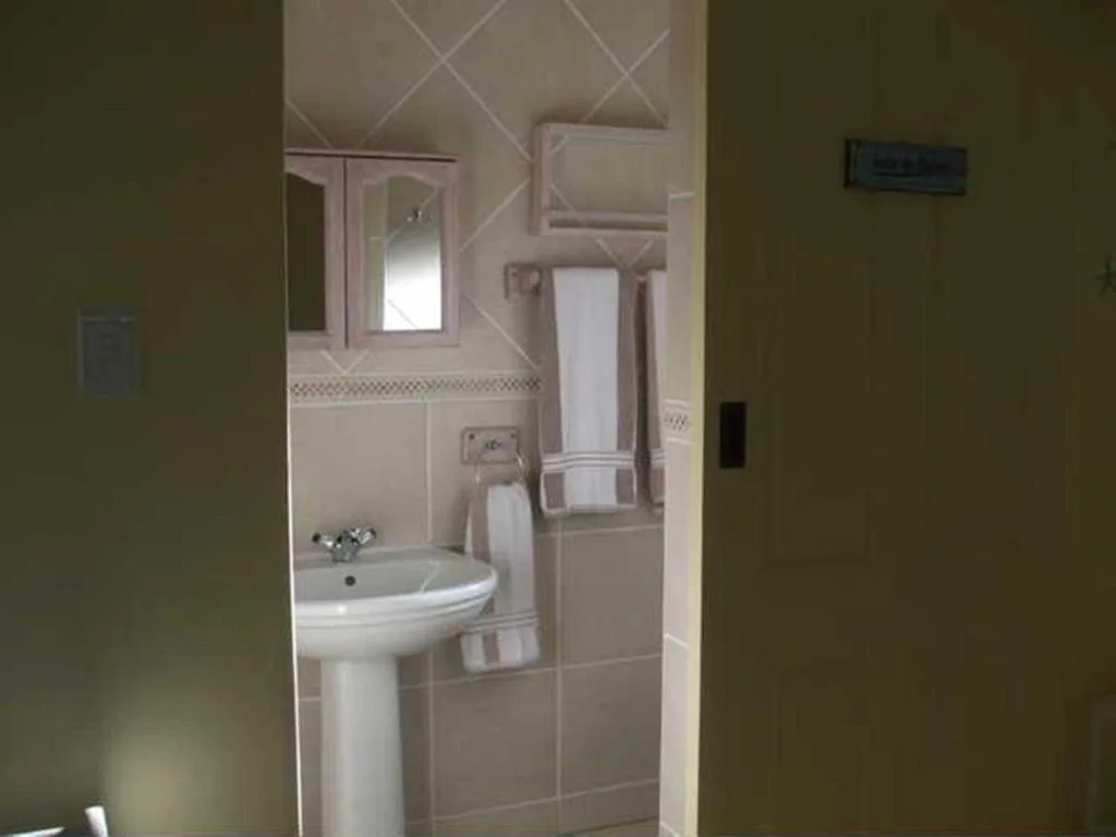 Compact bathroom with pedestal sink, mirror cabinet, and towel rack