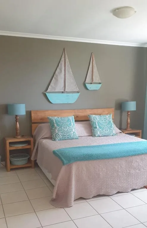 Bedroom with wooden bed, coastal decor sailboats, turquoise accents
