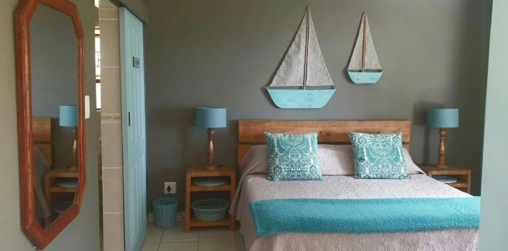 Coastal-themed bedroom with wooden bed, turquoise accents, and sailboat decor