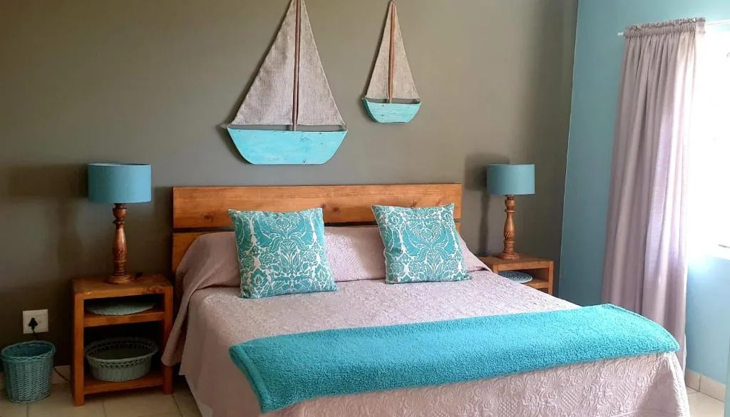 Coastal-themed bedroom with wooden bed, turquoise accents, and sailboat wall art