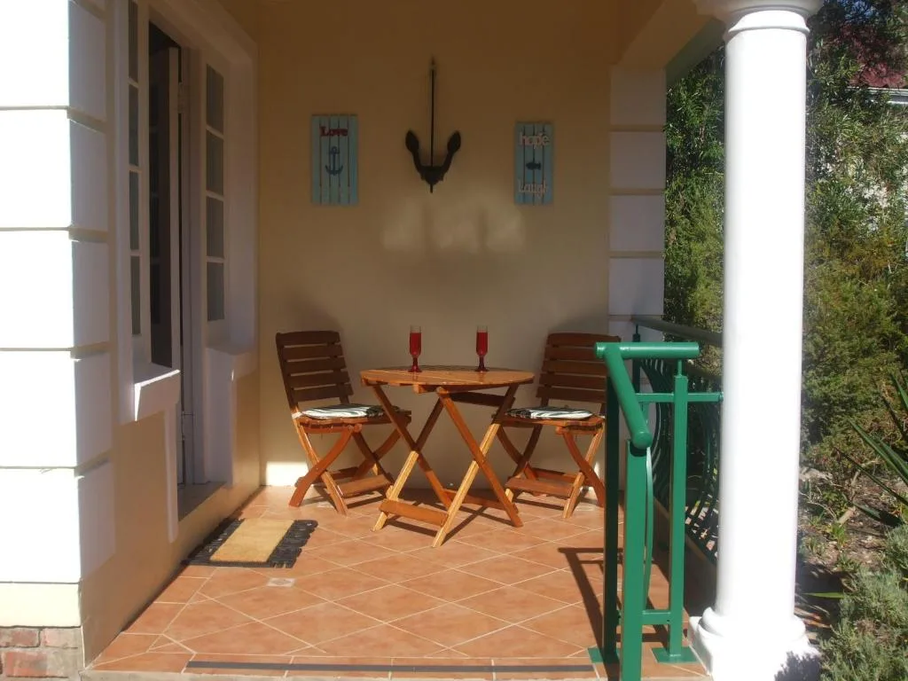 Covered patio with wooden chairs, small table, and climbing vines