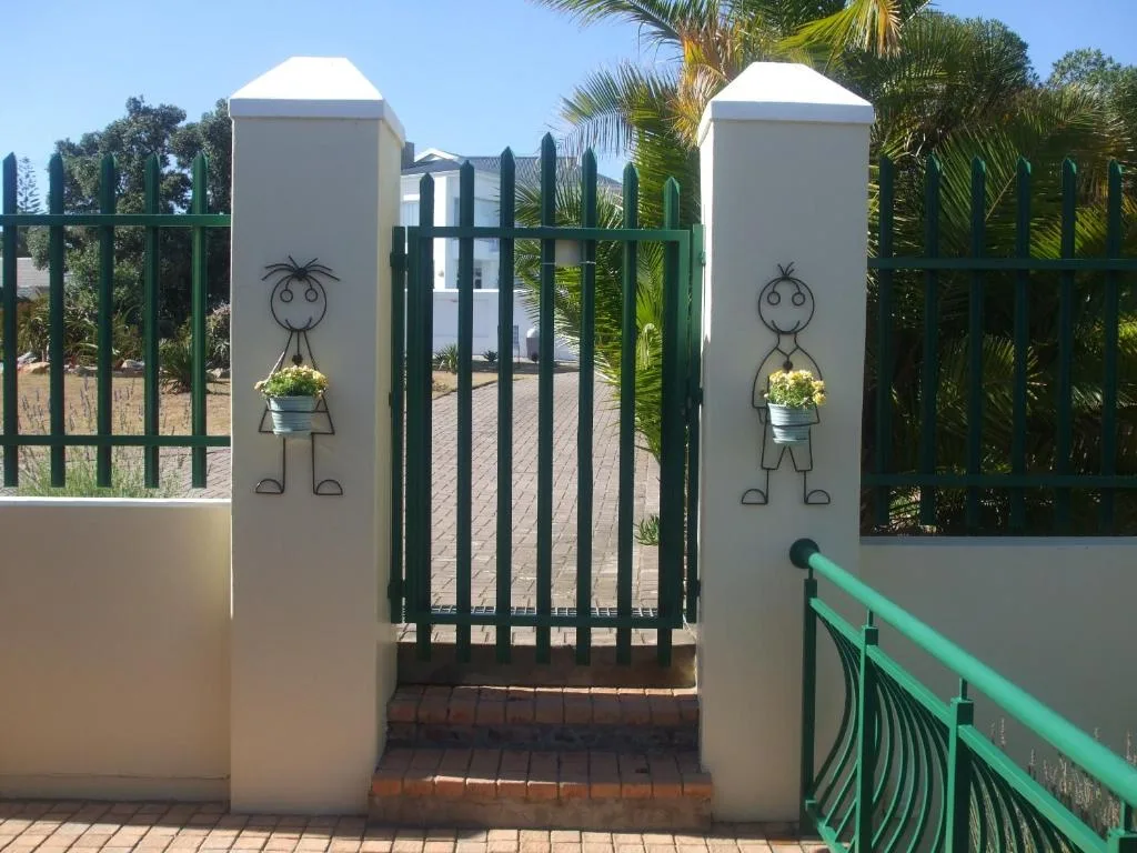 Charming property entrance with white pillars and green gate