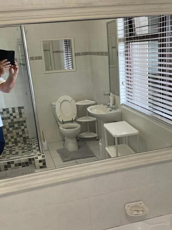 Clean bathroom with toilet, sink, mirror, and shower enclosure