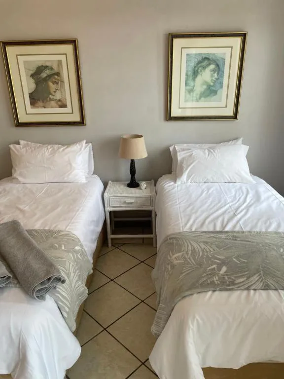 Twin bedroom with white linens, bedside table, and framed artwork