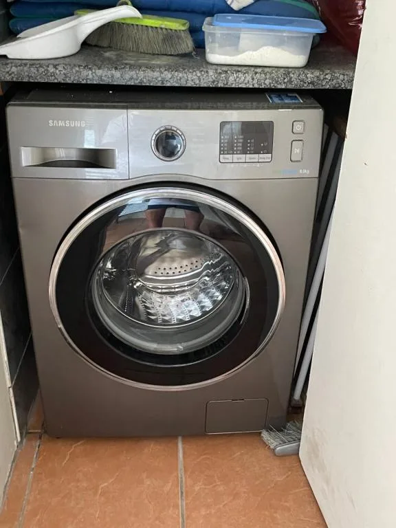 Modern Samsung washing machine in utility area with storage shelves above