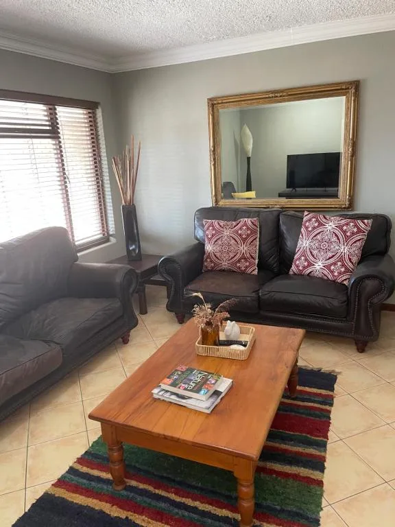 Comfortable living room with dark leather sofa, armchair, and wooden coffee table