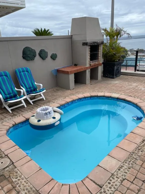 Bright blue swimming pool on rooftop deck with loungers and ocean view