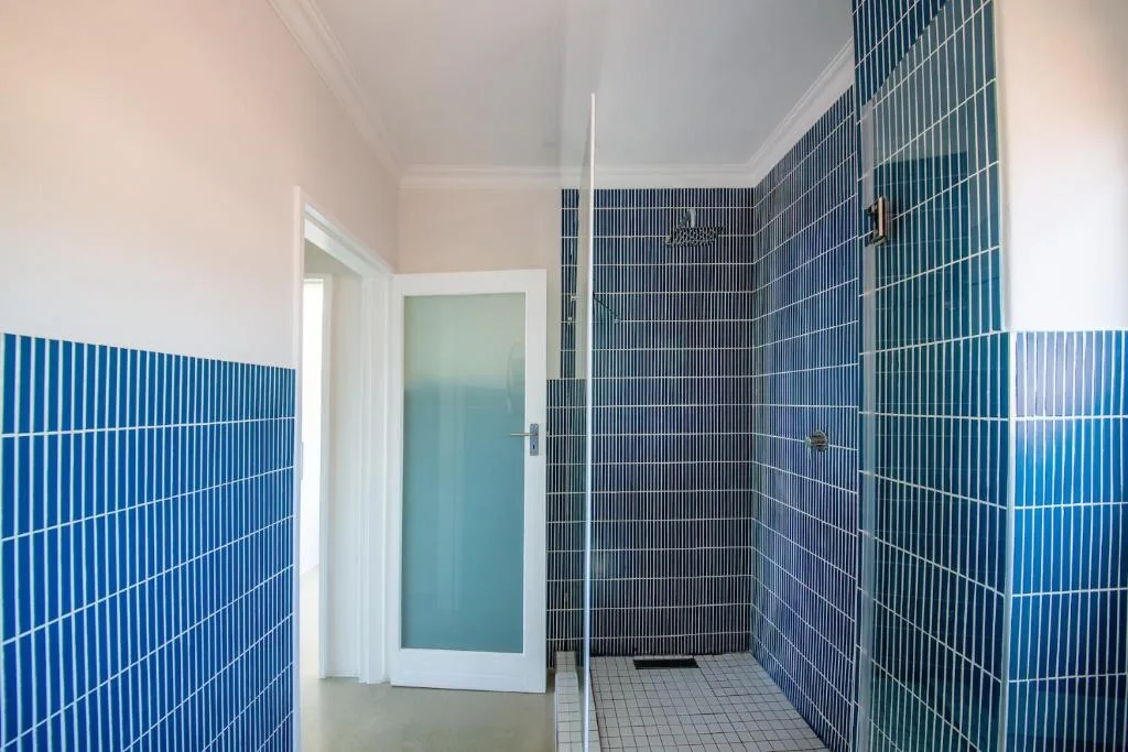 Modern bathroom with blue tile walls and walk-in shower enclosure