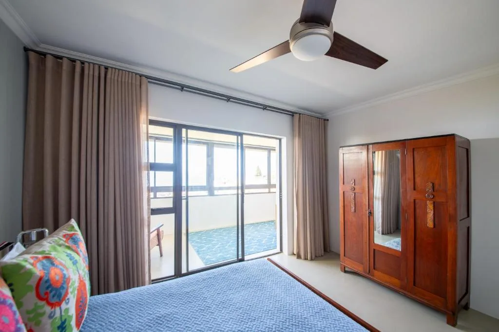 Bright bedroom with pool view, wooden wardrobe, and ceiling fan
