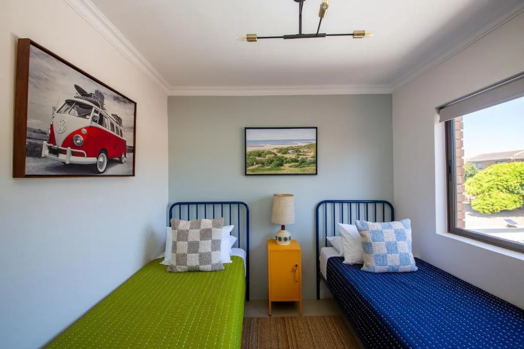 Twin bedroom with green and blue beds, colorful decor and artwork