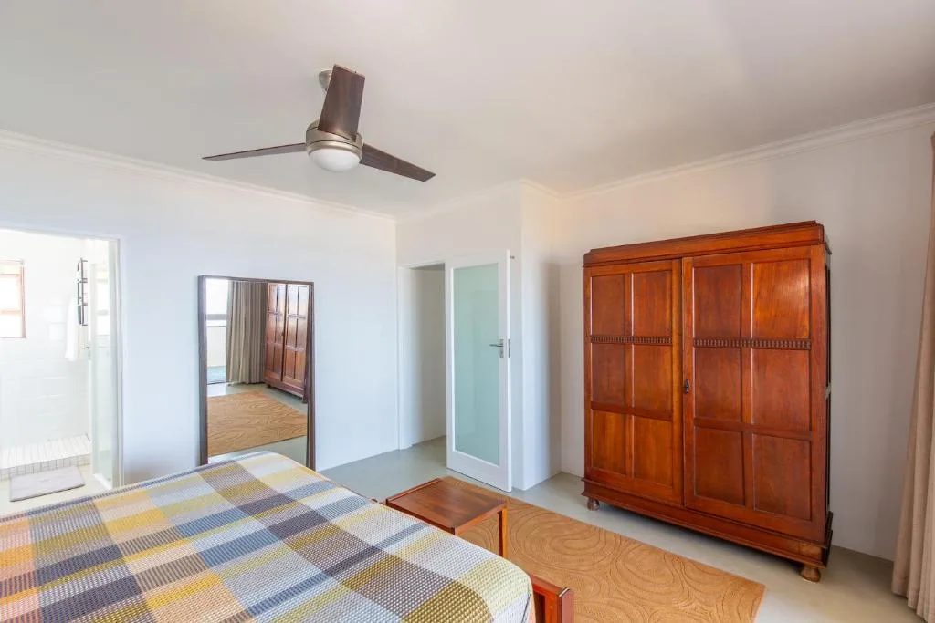 Bright bedroom with double bed, wooden wardrobe, and ceiling fan