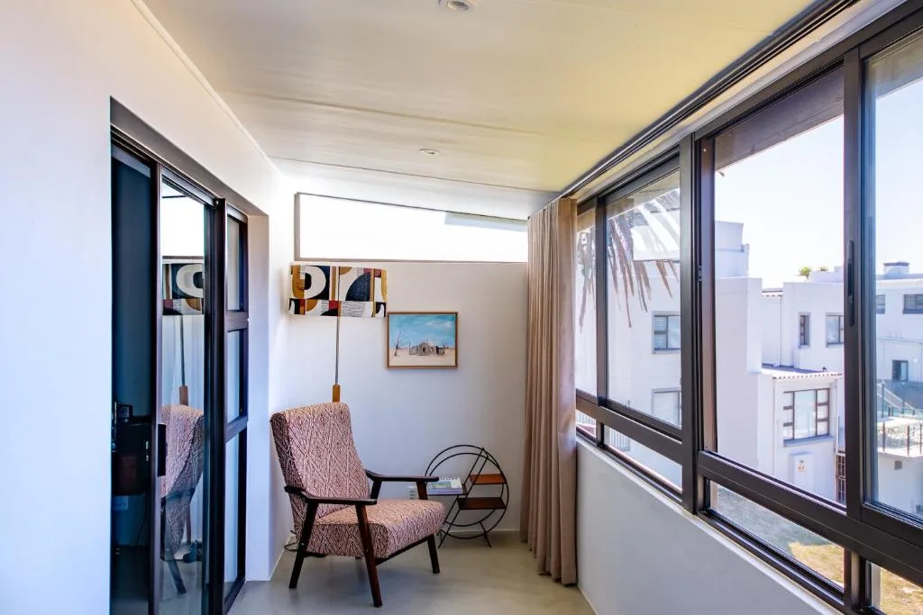 Bright balcony with comfortable armchair overlooking town buildings and streetscape