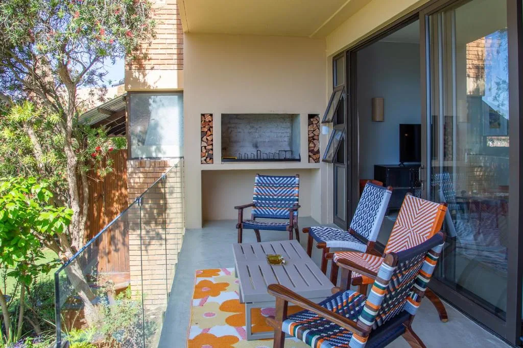 Covered patio with wooden chairs, fireplace, and sliding glass doors