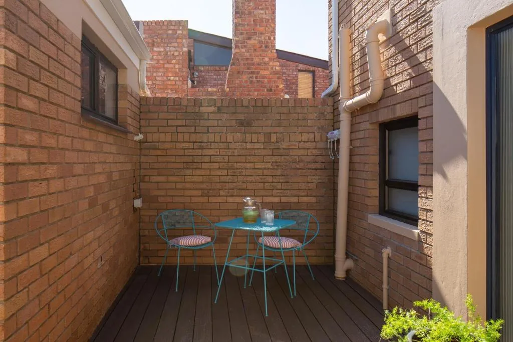Outdoor patio with turquoise table and chairs, brick walls, dark decking
