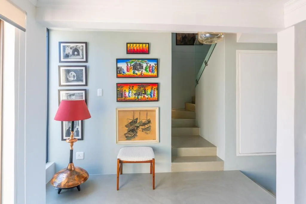 Hallway with framed artwork, decorative lamp, and wooden stool